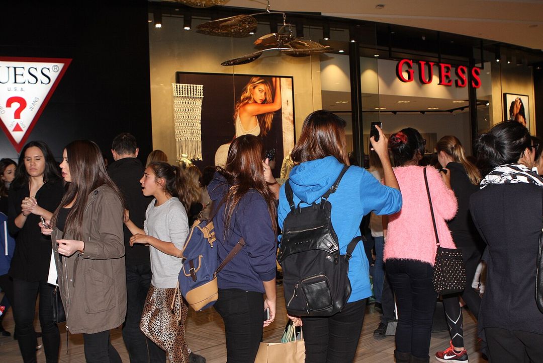 Façade d'une boutique Guess éclairée le soir, avec des vitrines.