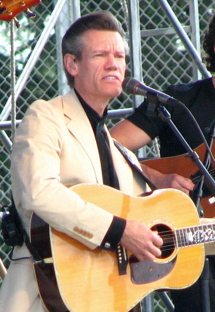 Randy Travis chantant sur scène en chapeau de cow-boy.